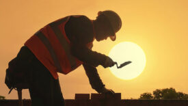 man laying bricks in summer heat