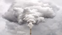 Smoke from factory pipe against dark overcast sky